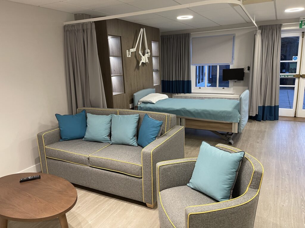 Inpatient unit room with sofas, armchair coffee table, bed and television
