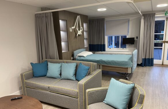 Inpatient unit room with sofas, armchair coffee table, bed and television