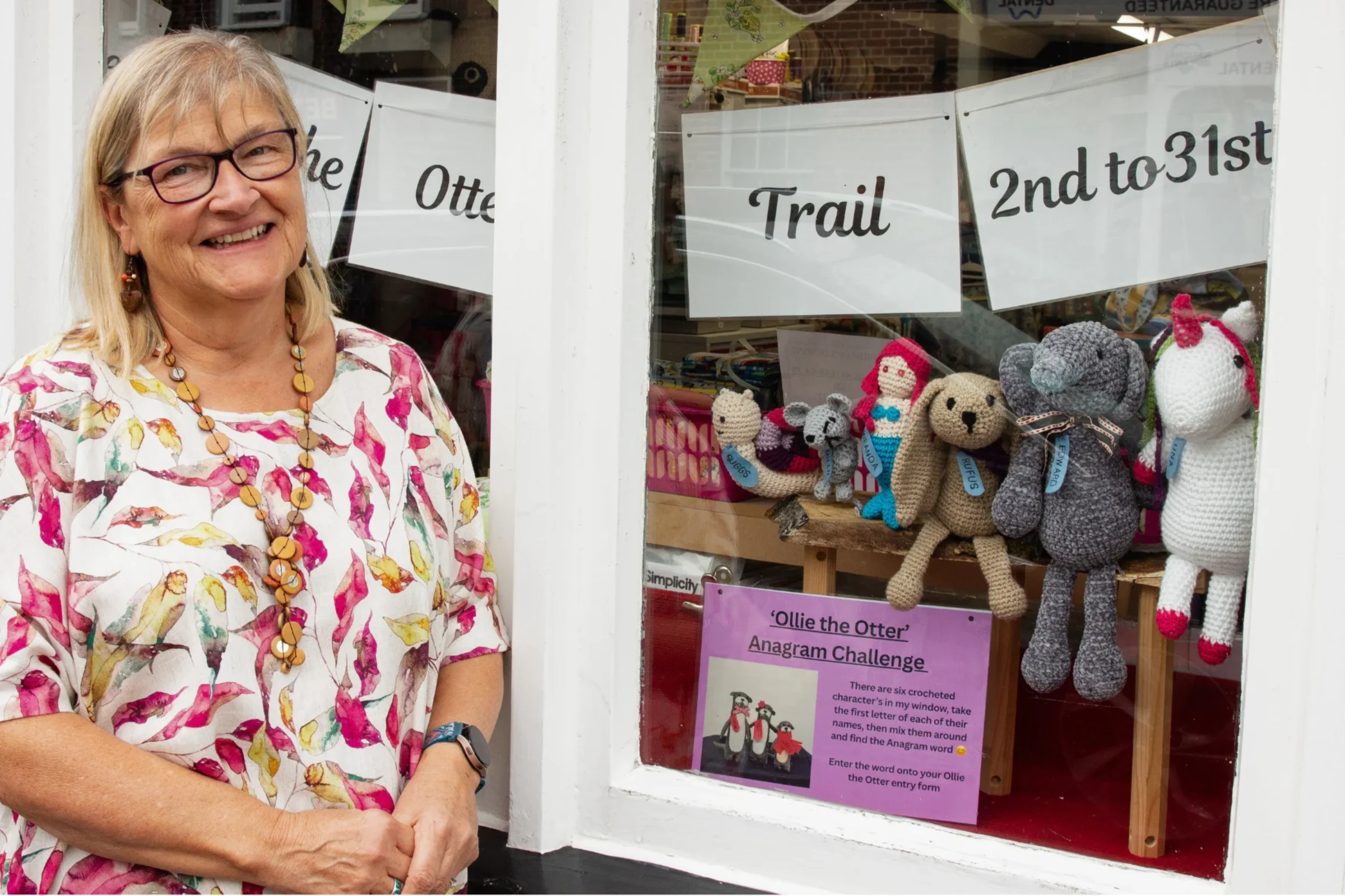 Marian Howells, owner of Cotton Moon in Blandford Forum, standing in front of some trail characters in her shop window